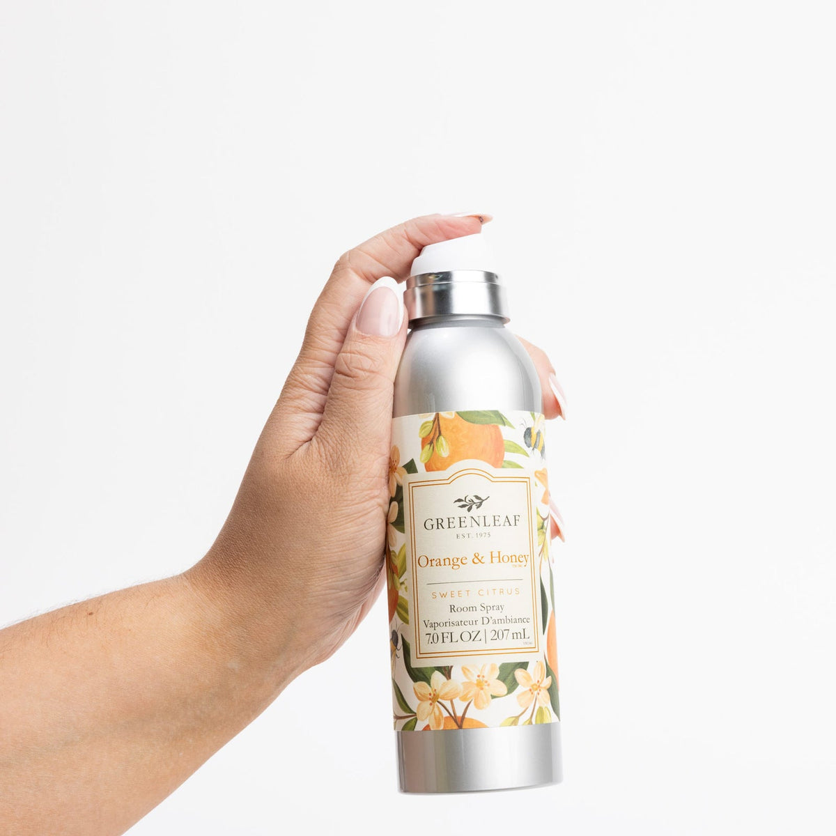 Hand holding a Greenleaf Orange & Honey diffuser bottle against a white background