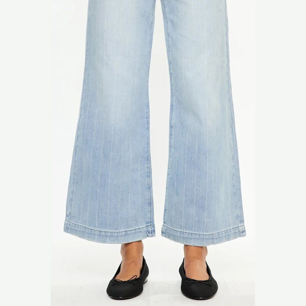 Close-up of light wash 90s wide-leg jeans with vertical pinstripes and black ballet flats on a white background.