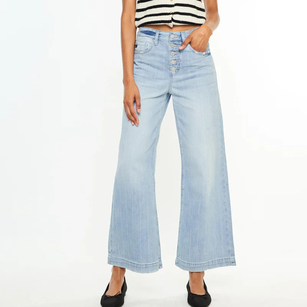 Woman in light wash, button-fly wide leg jeans with subtle vertical stripes and black ballet flats.