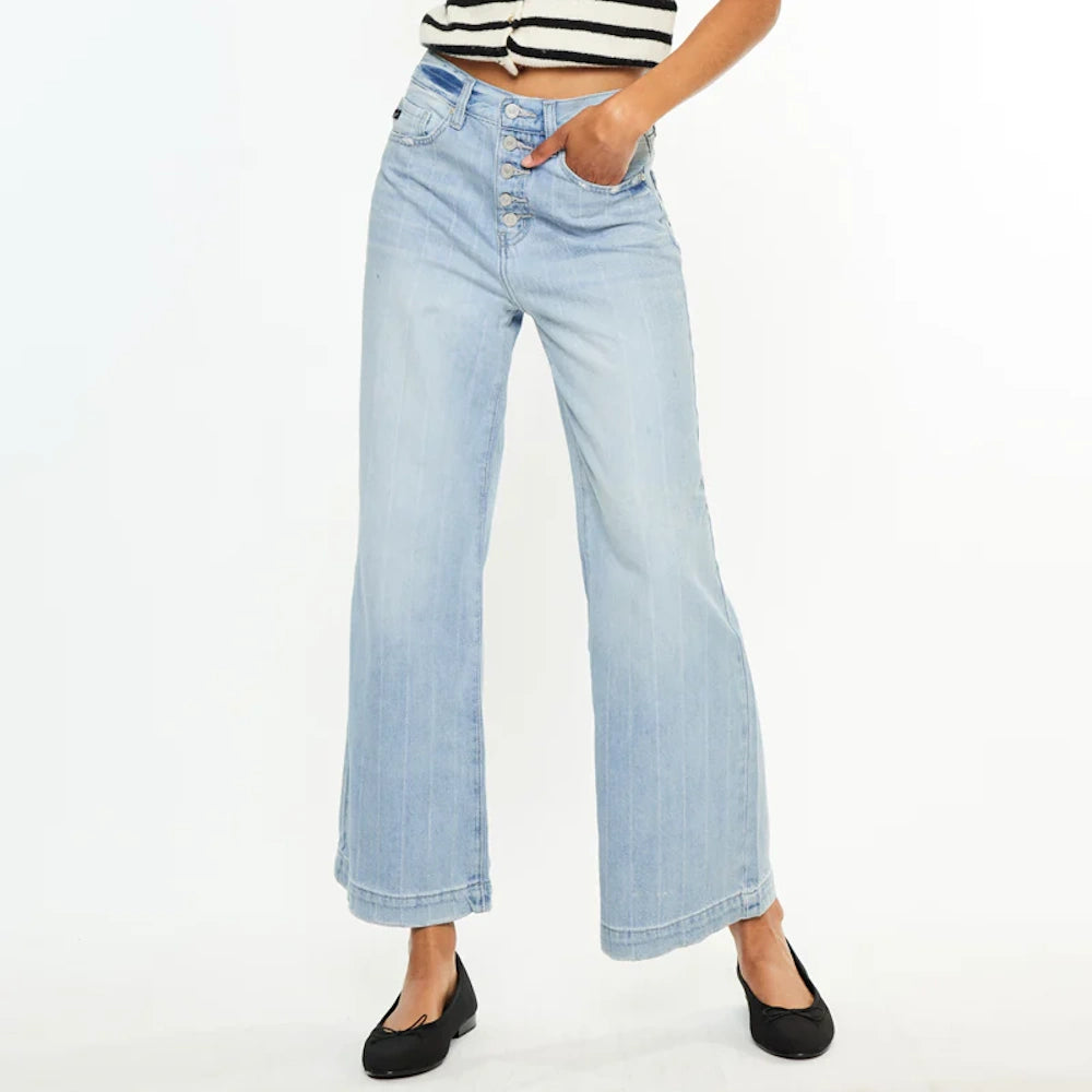 Model in light wash 90s wide-leg jeans with button fly, striped top, and black ballet flats on white background.