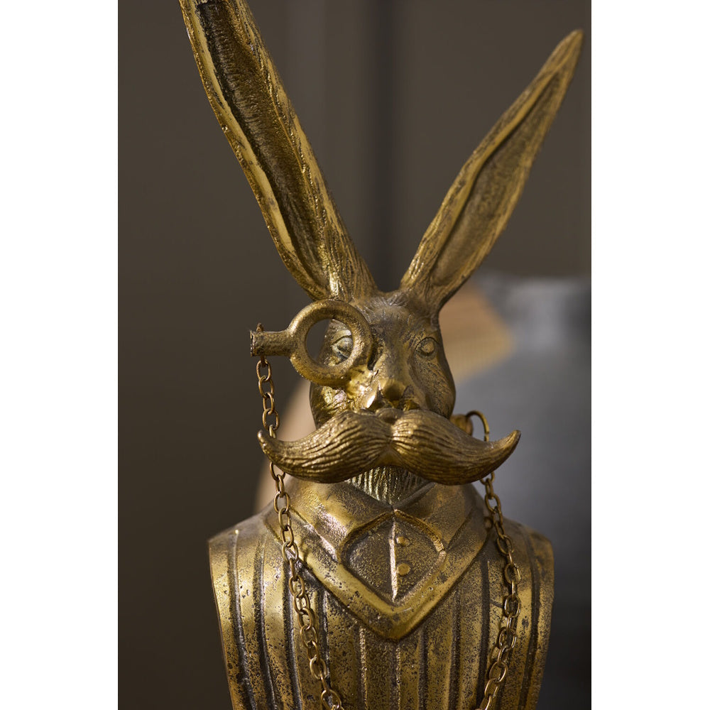 Close-up front view of the antique gold rabbit bust highlighting its detailed monocle, chain, and mustache.
