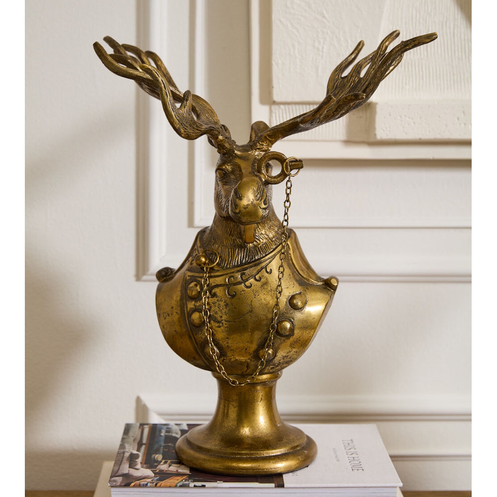 Front view of a gold resin Eugene the Moose bust figurine styled with a monocle and chain, displayed on top of a book.