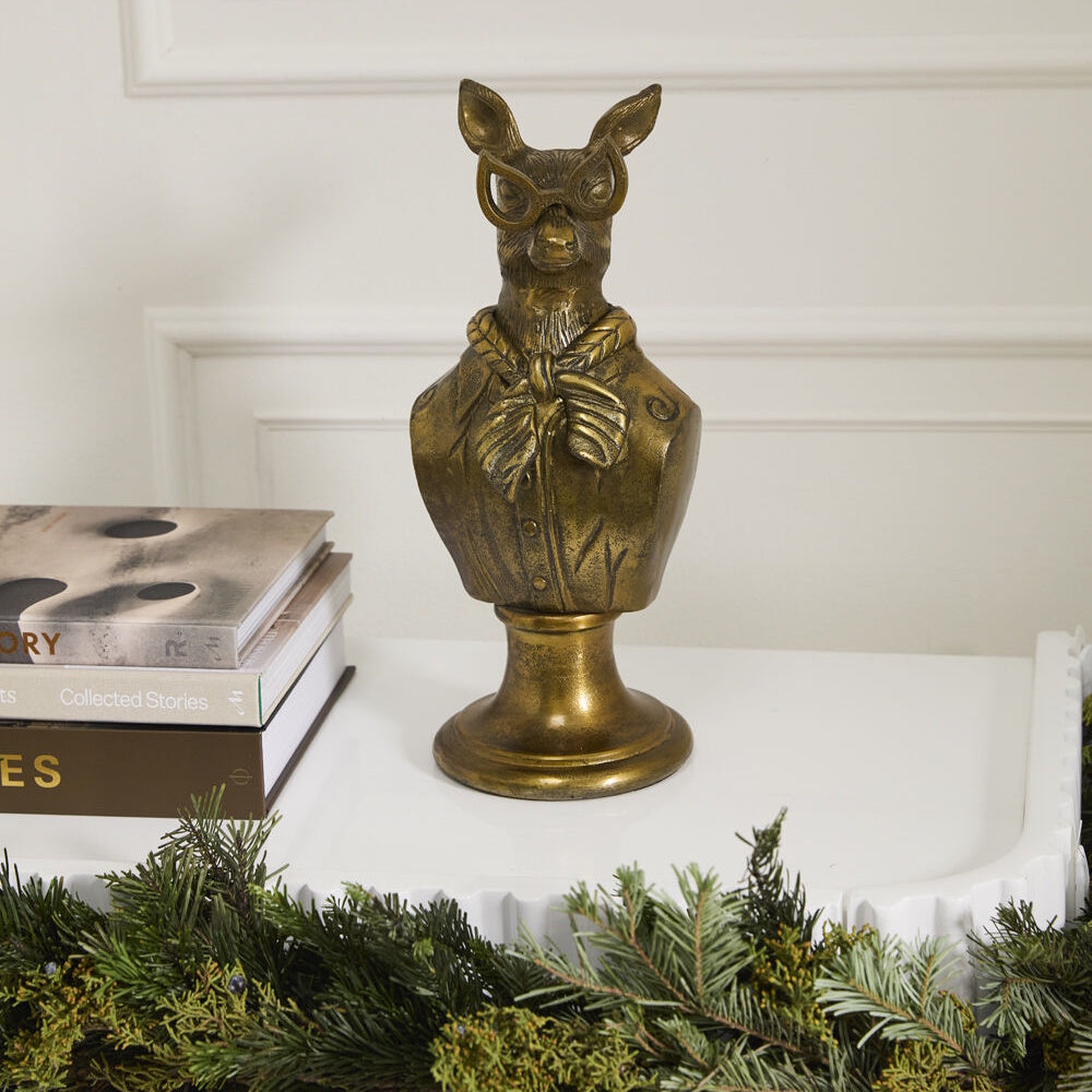 Front view of the antique gold doe bust displayed on a white surface next to stacked books.