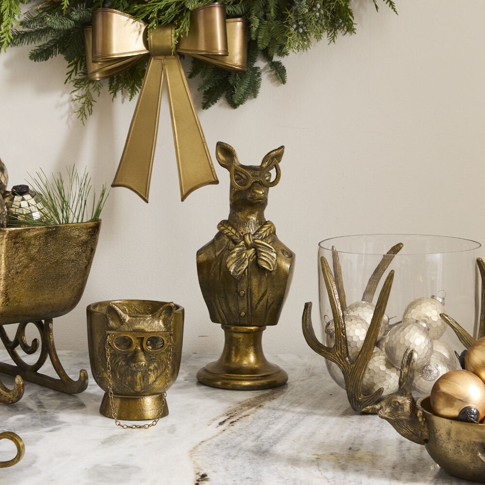Front view of the antique gold doe bust displayed on a white mantelpiece with holiday greenery and books.