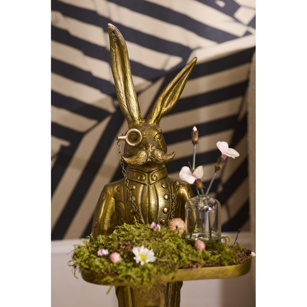 Golden rabbit butler figurine with a monocle and mustache, holding a tray with moss and flowers.