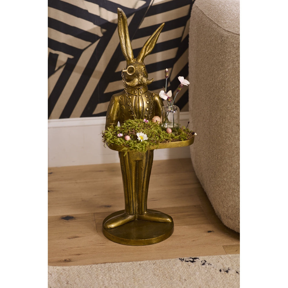 Gold rabbit butler statue with monocle holding a tray with moss and flowers.