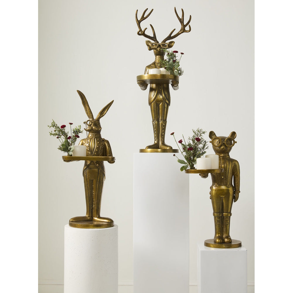 Three gold animal butler statues holding trays with candles and small floral arrangements.