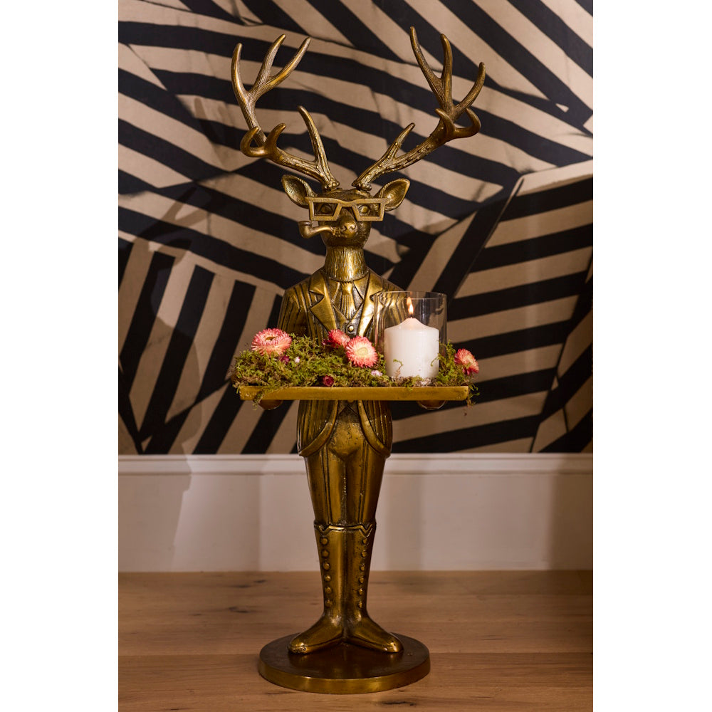 Gold deer butler statue in a suit holding a tray with flowers and a lit candle.