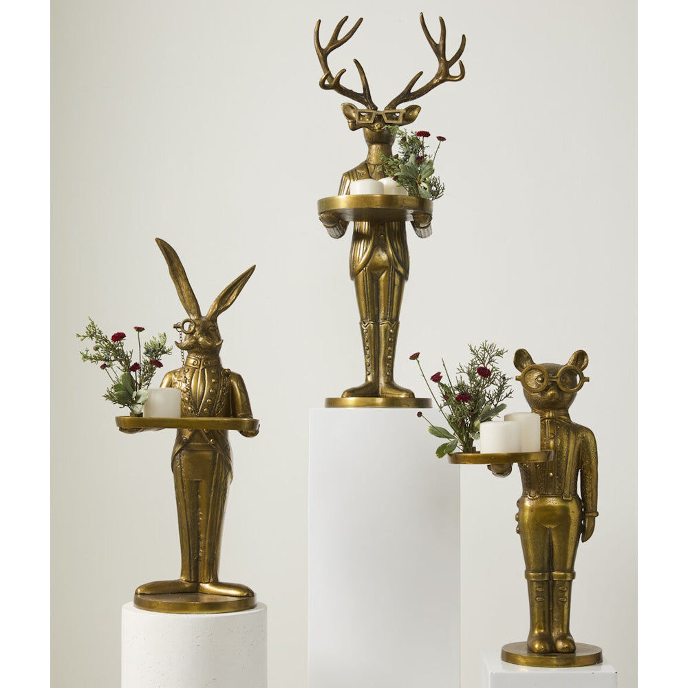 Three gold animal butler statues holding trays with candles and flowers.