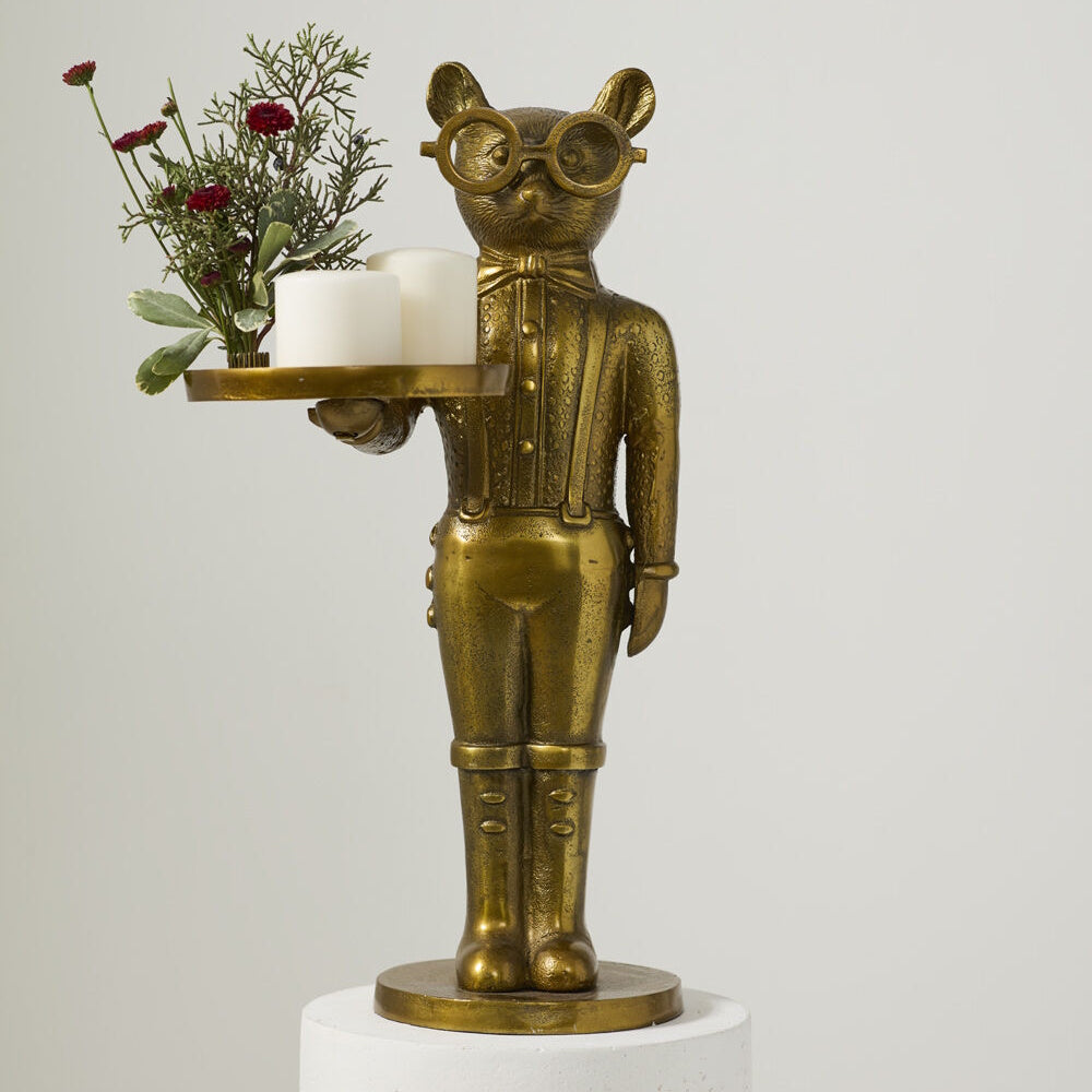 Gold cat butler statue wearing glasses, holding a tray with candles and flowers on a white background.