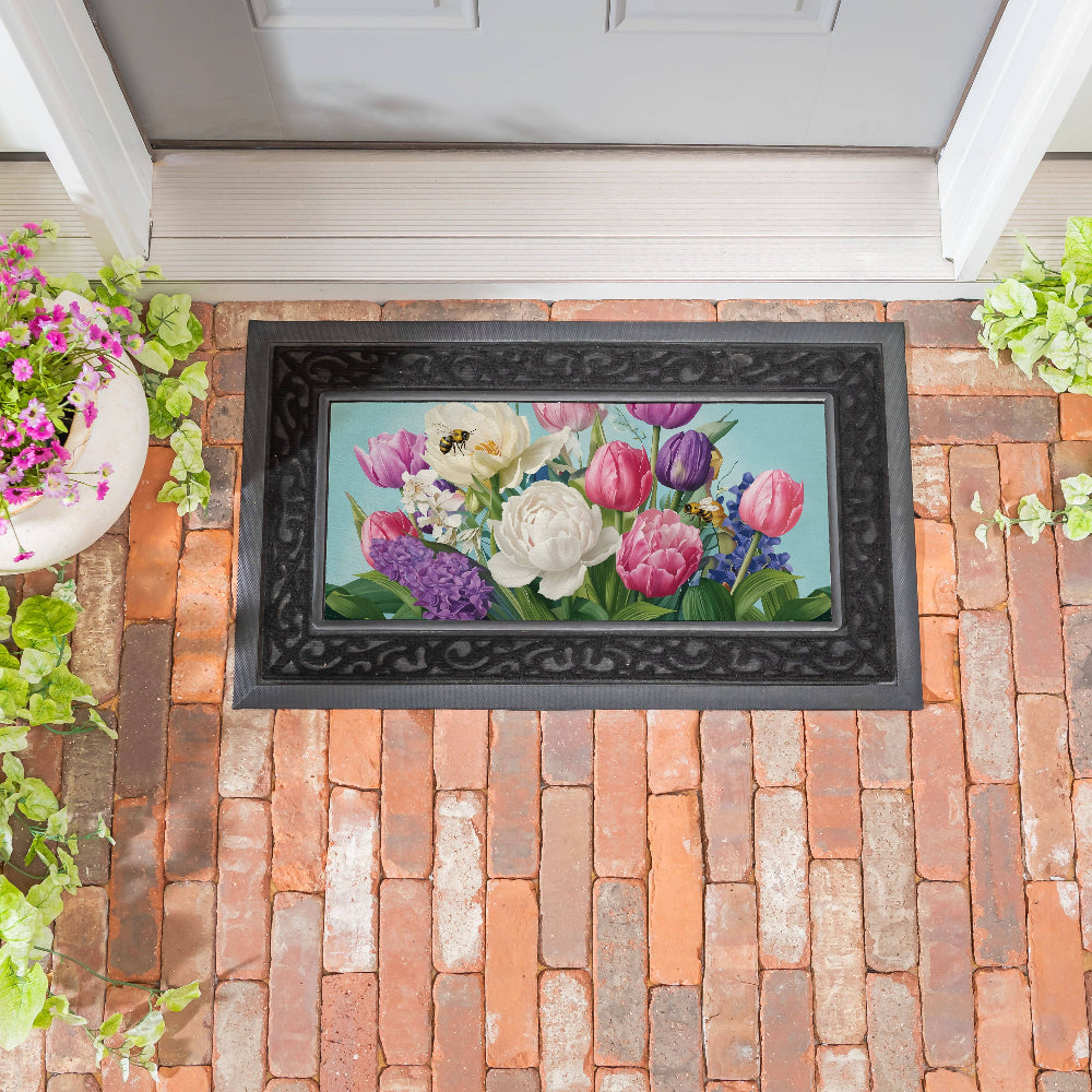 A decorative spring floral and bee motif mat on a brick entryway.
