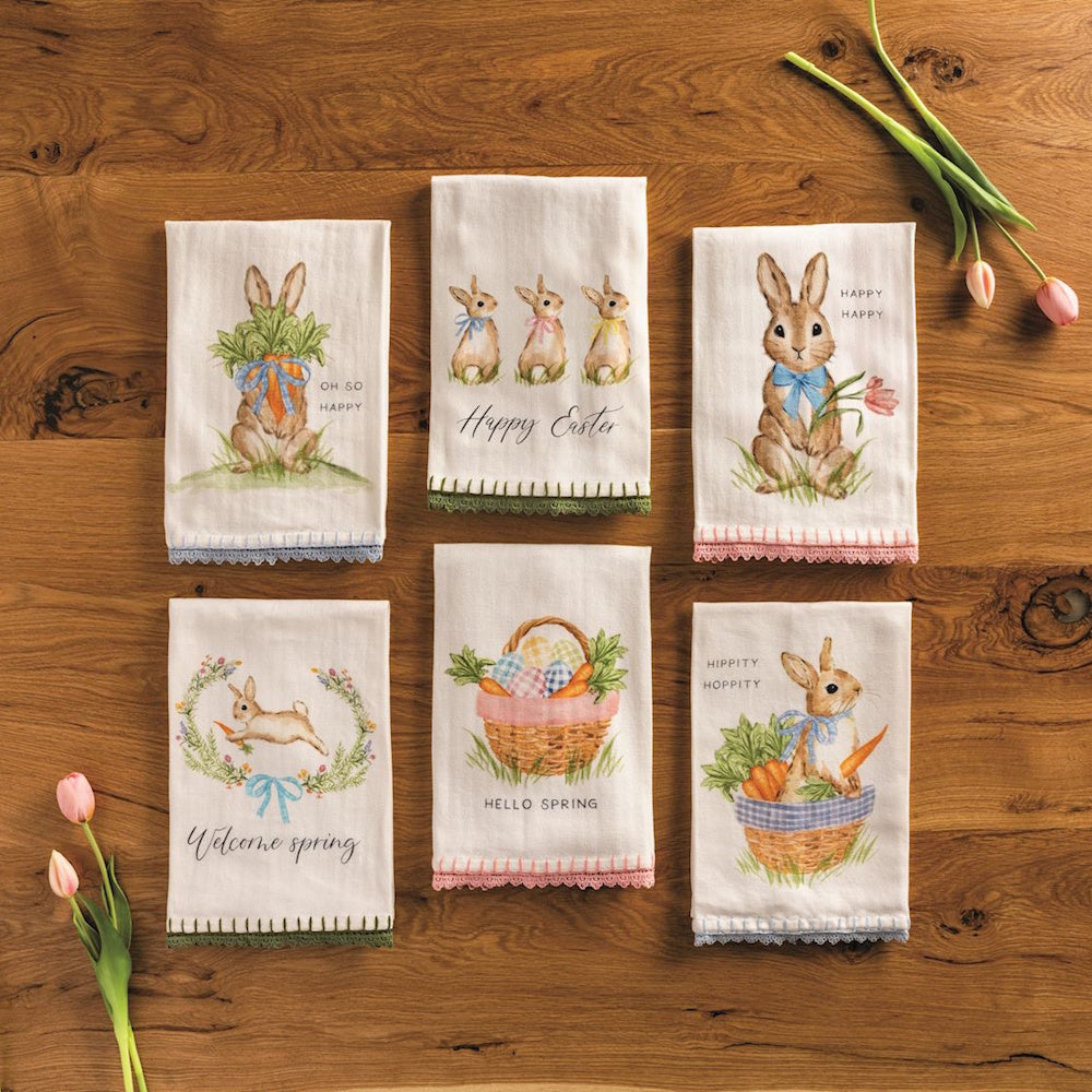 Easter tea towels with bunny illustrations, spring sayings, and decorative lace trim on a wooden background.
