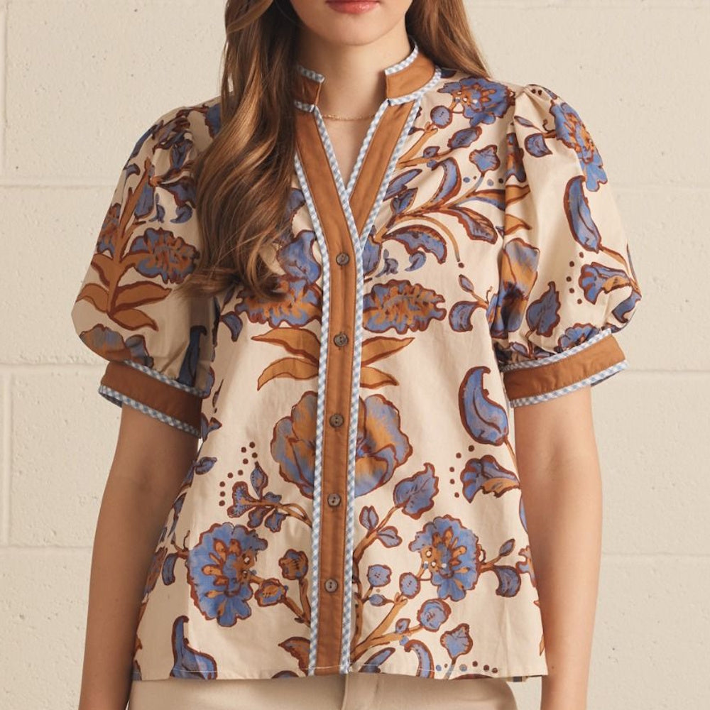 Ecru floral print top featuring blue and tan flowers, short puff sleeves, and a brown placket.