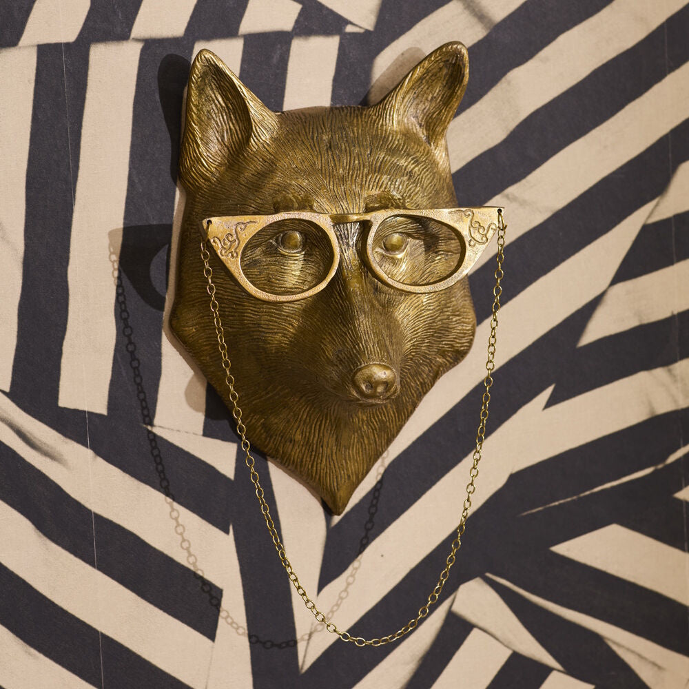 Gold fox head wall hook wearing cat-eye glasses with a hanging chain, set against a striped background.