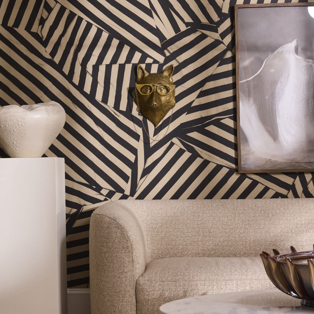 Gold fox head wall mount with glasses on striped geometric wallpaper above a neutral textured sofa.
