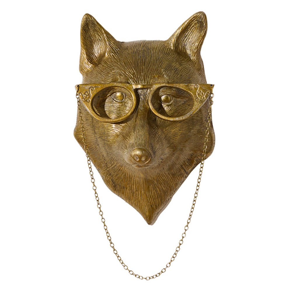 Gold brass fox head wall mount wearing ornate cat-eye glasses with a hanging chain on white background.
