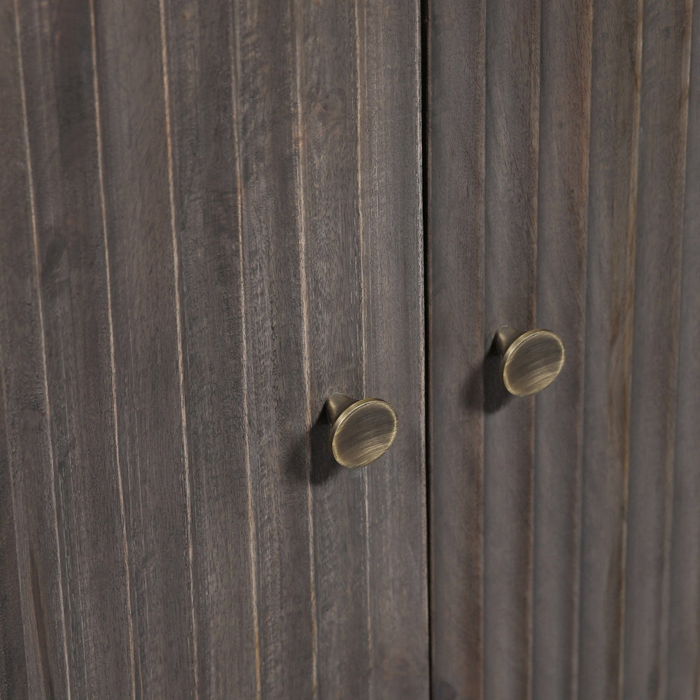Close-up view of antique brass round pulls on dark grey fluted wood cabinet doors.