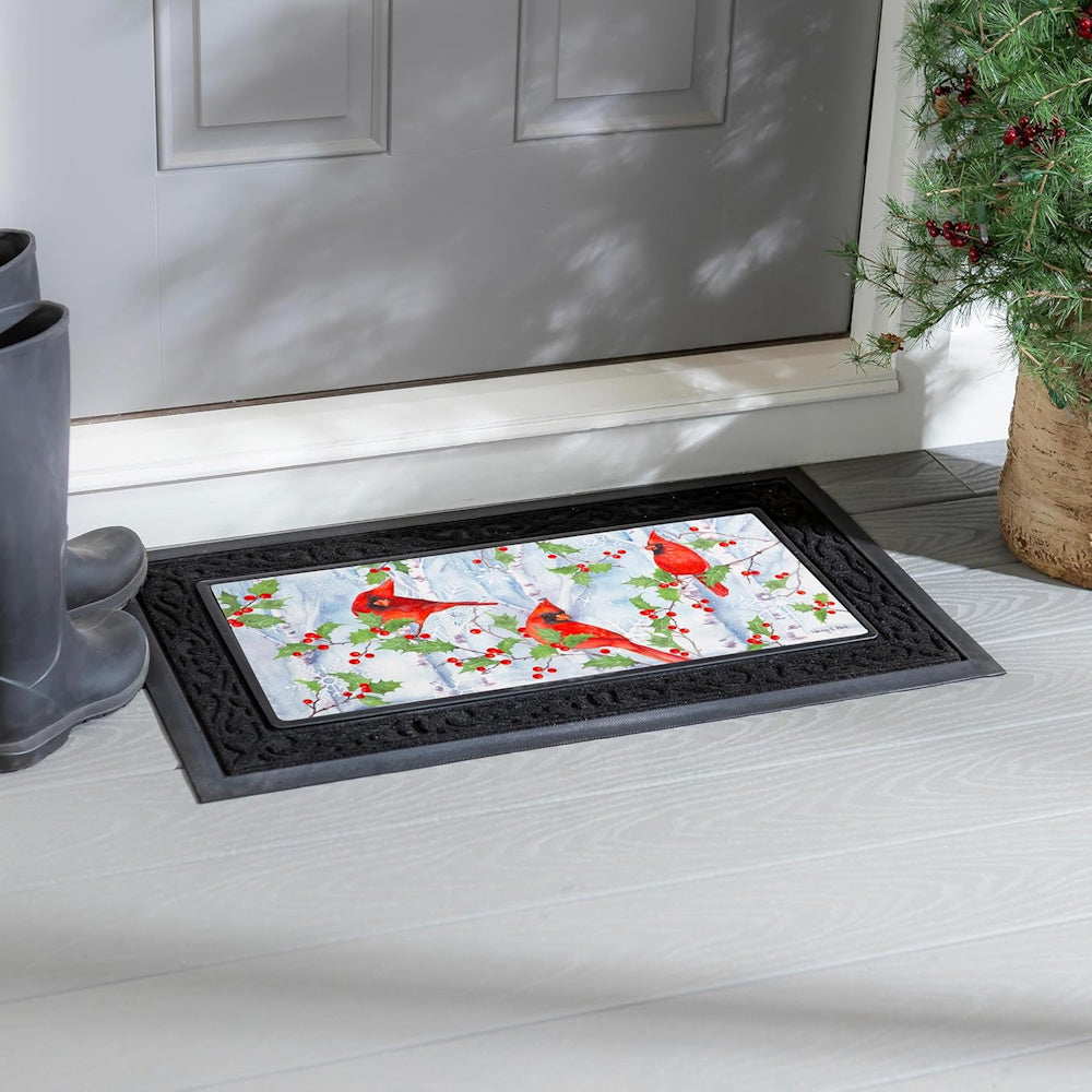 Winter doormat with red cardinals on birch branches with holly berries, set in a black decorative rubber tray.