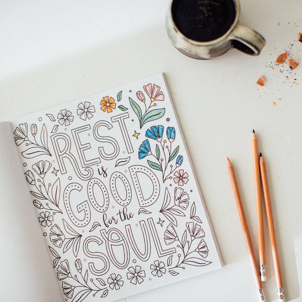 Adult coloring book page with the quote "Rest is good for the soul" surrounded by floral designs, pencils, and coffee.
