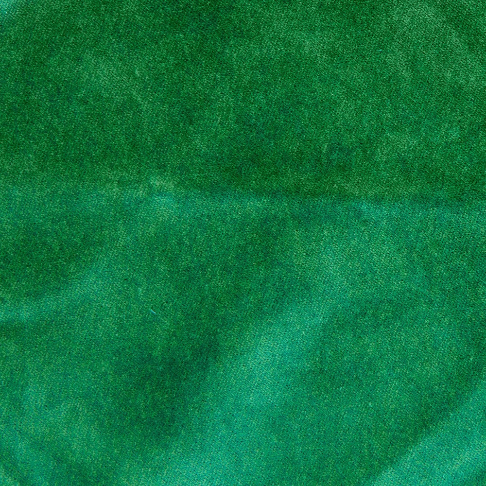 Close-up of emerald green velvet sofa fabric texture with soft shadows and rich, jewel-toned plush fibers.