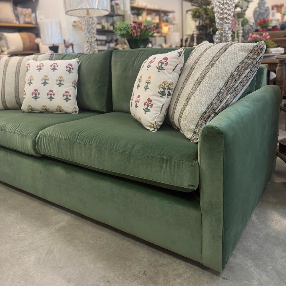Emerald green velvet Banks sofa featuring striped and floral throw pillows in a boutique home furniture showroom setting.