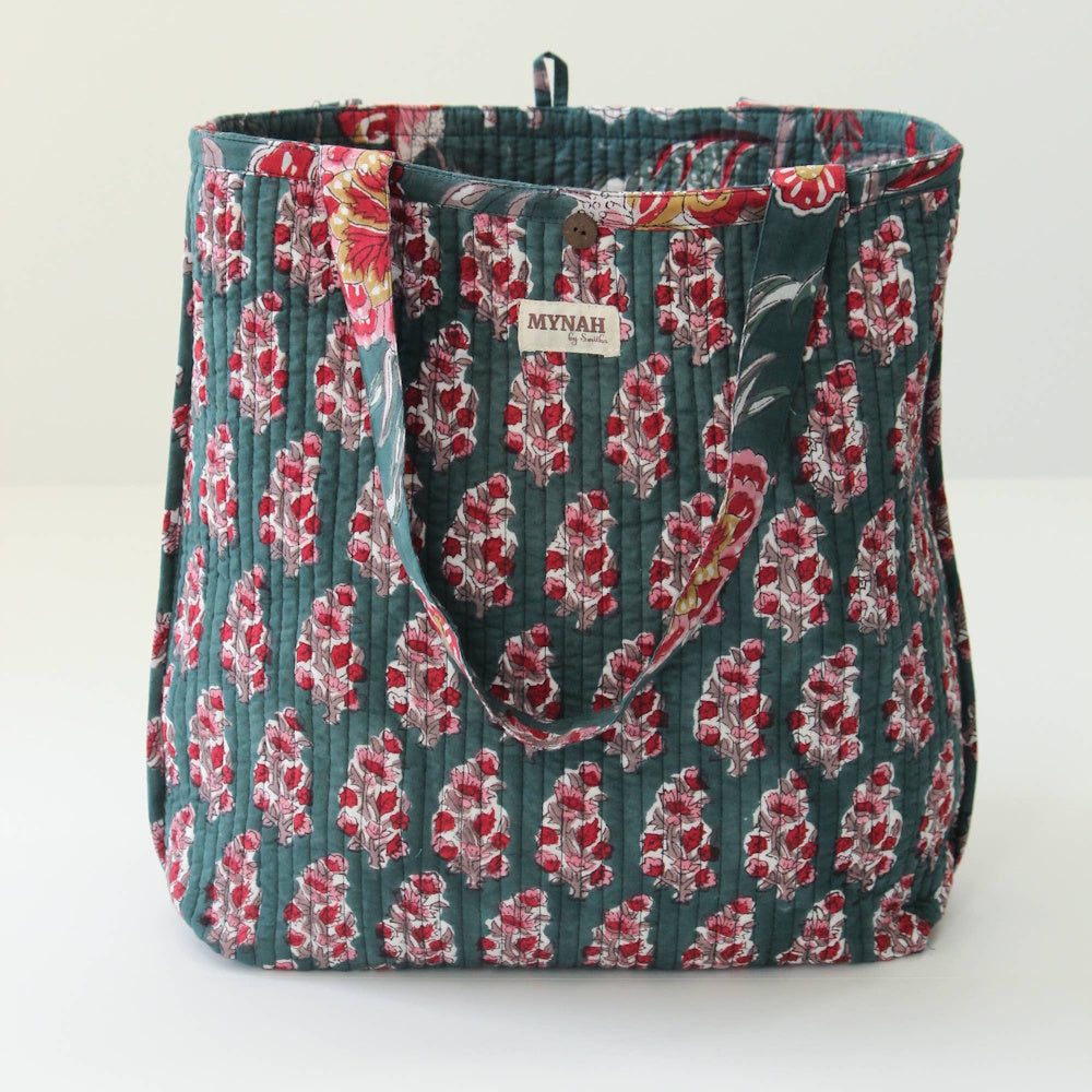 Reversible emerald green quilted tote bag featuring a pink floral bud block print pattern and a small Mynah brand tag.