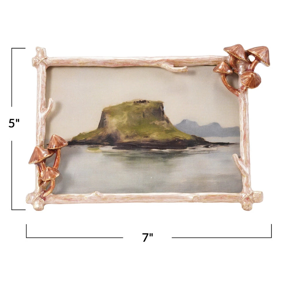 Mushroom and twig enameled metal photo frame with 5-inch by 7-inch dimension markers shown over an island landscape.