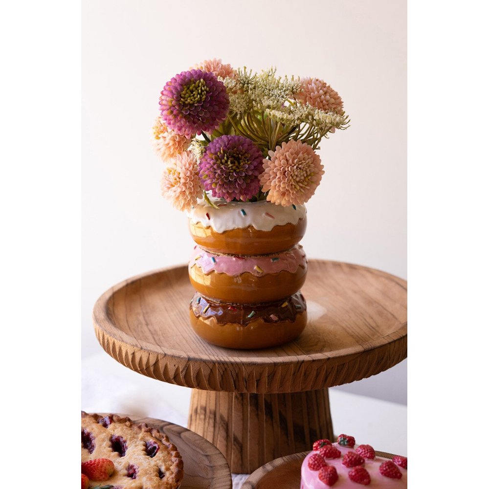 Etched wooden pedestal stand holding a stacked donut vase filled with colorful flowers.