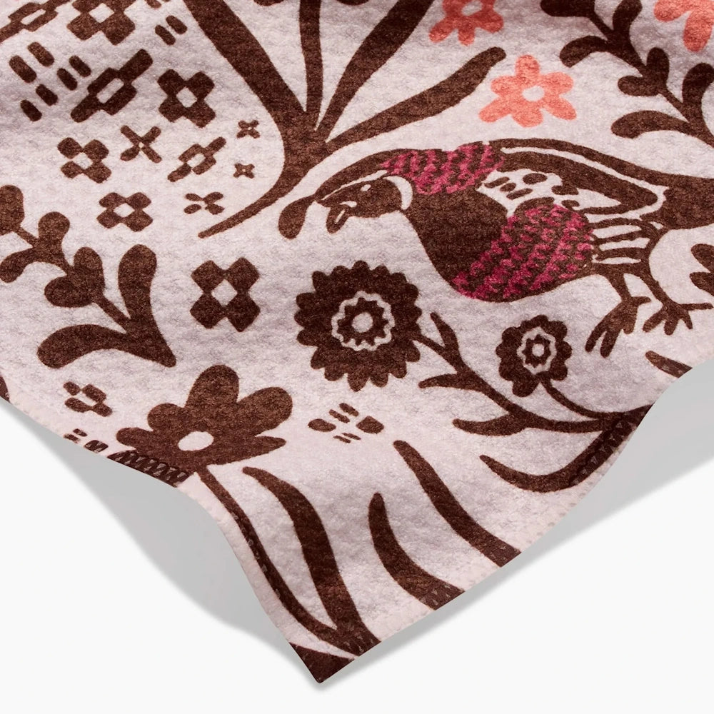 Close-up of a pink patterned towel featuring a brown and magenta bird surrounded by autumn flowers.