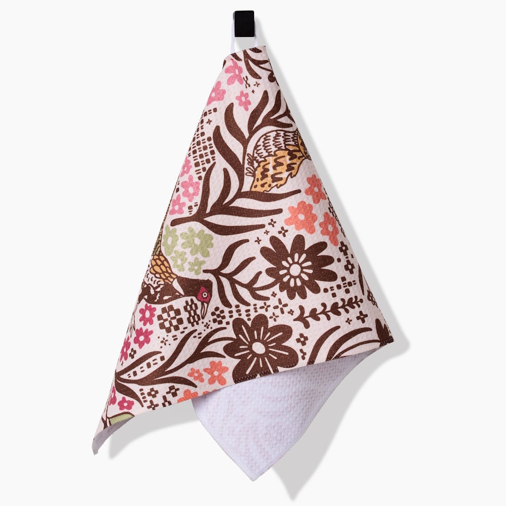 Patterned towel with birds and flowers hanging from a loop, showing a white textured underside.
