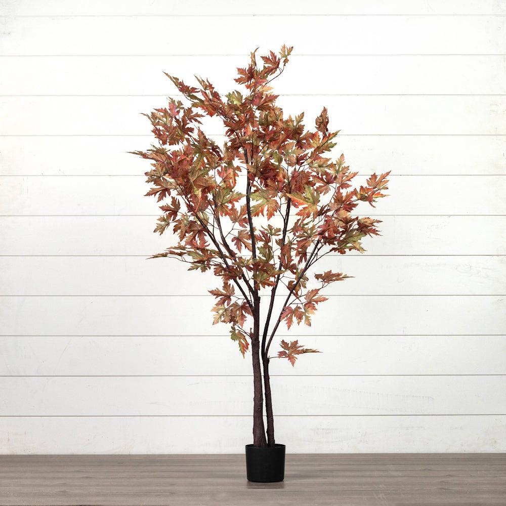 Artificial autumn maple tree with potted base featuring reddish-brown foliage against a white wall.