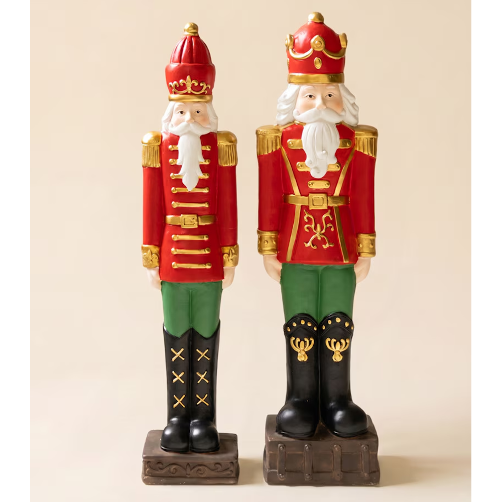 Full-length view of two faux concrete Christmas nutcracker soldiers standing on decorative bases.