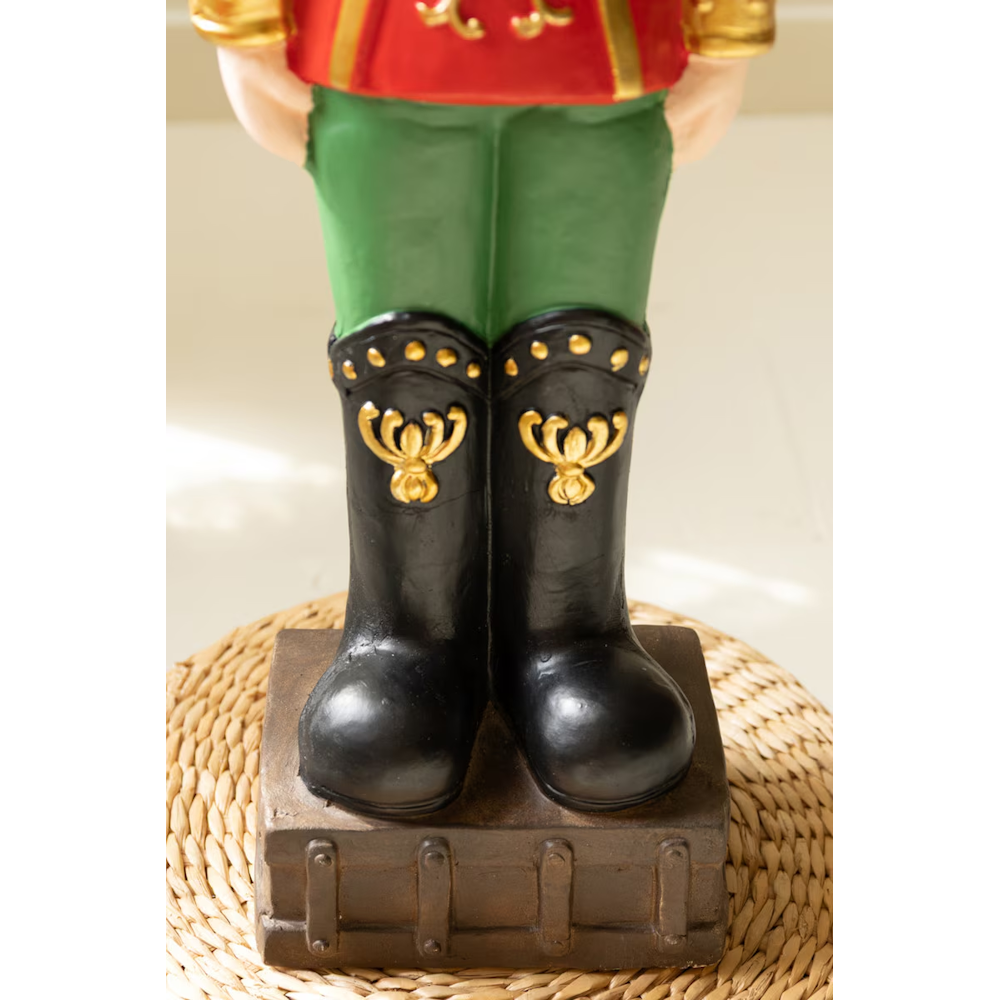 Detailed view of the base and black boots of a faux concrete Christmas nutcracker soldier statue.