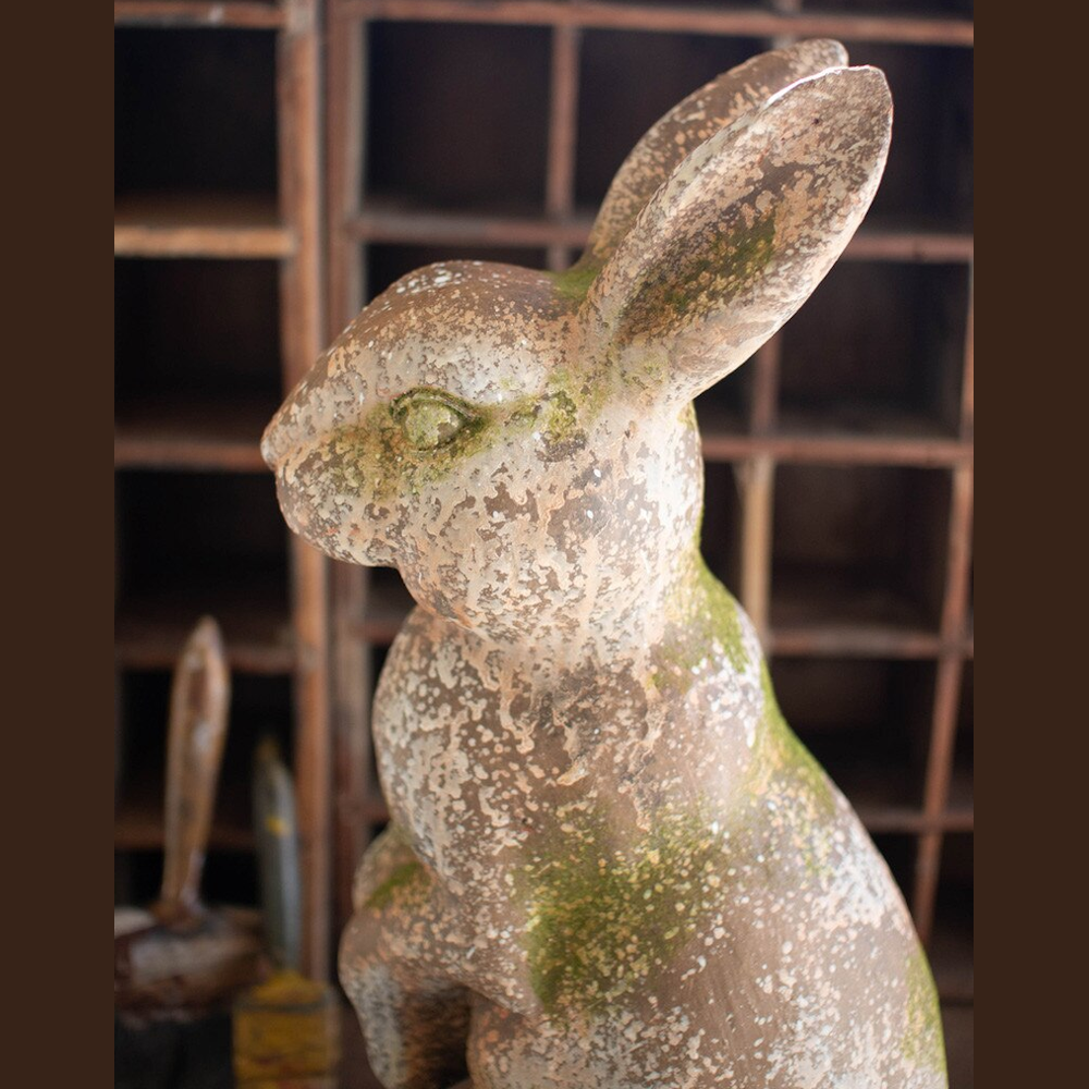Profile view of a rustic faux-concrete rabbit statue with weathered moss details and a vintage stone finish.