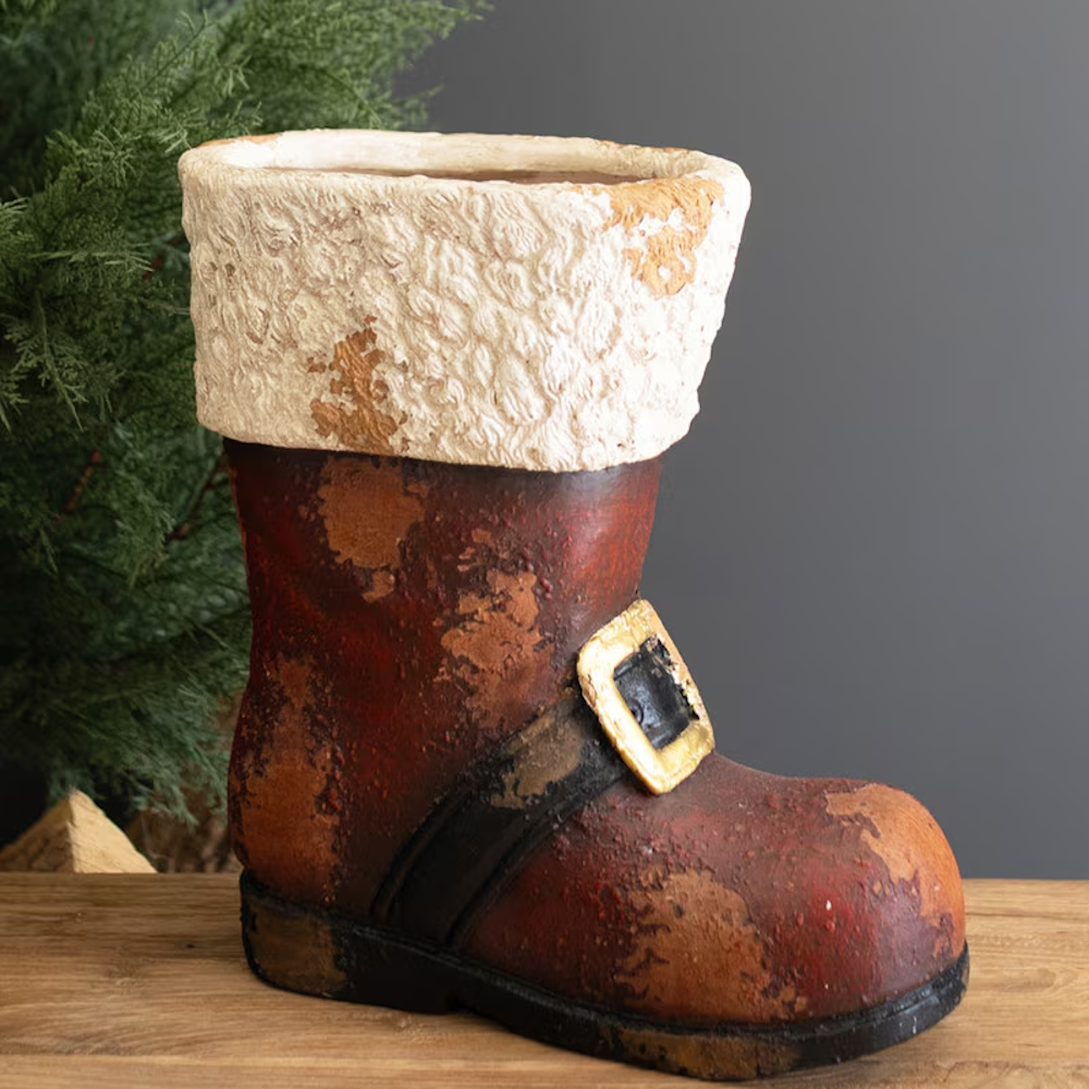 Rustic faux-concrete Santa boot planter with a distressed finish on a wooden surface.