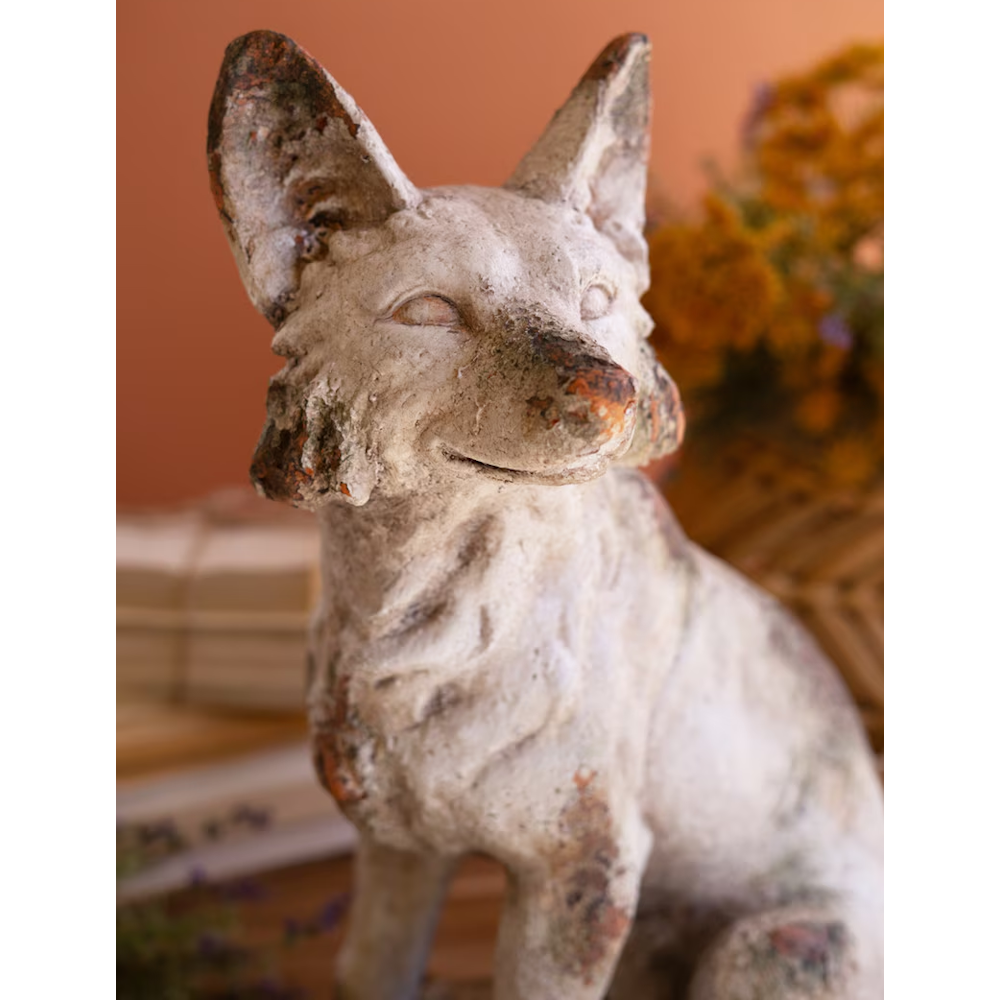 Close-up view of a rustic, weathered fox statue showing its textured face and faux-concrete finish.