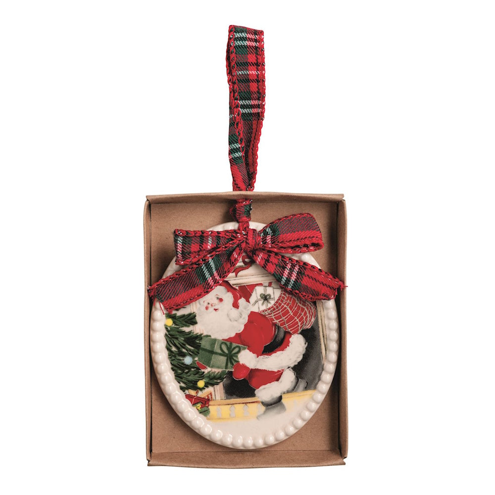 Oval ceramic Christmas ornament depicting Santa Claus by a tree, topped with a plaid ribbon bow.