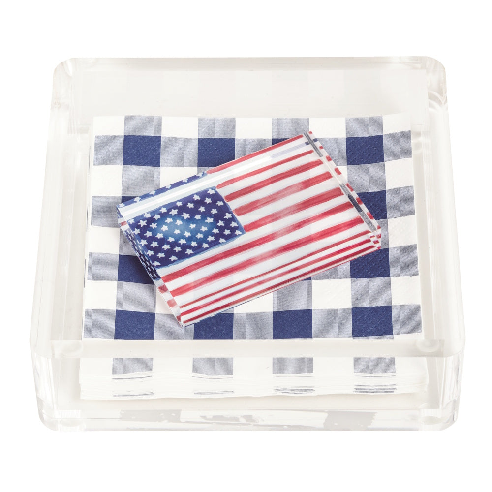 American flag acrylic napkin weight on blue gingham napkins in a clear square holder, patriotic table decor.