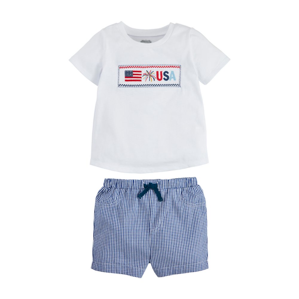 A white t-shirt with a smocked USA flag and firework design paired with blue and white gingham shorts.