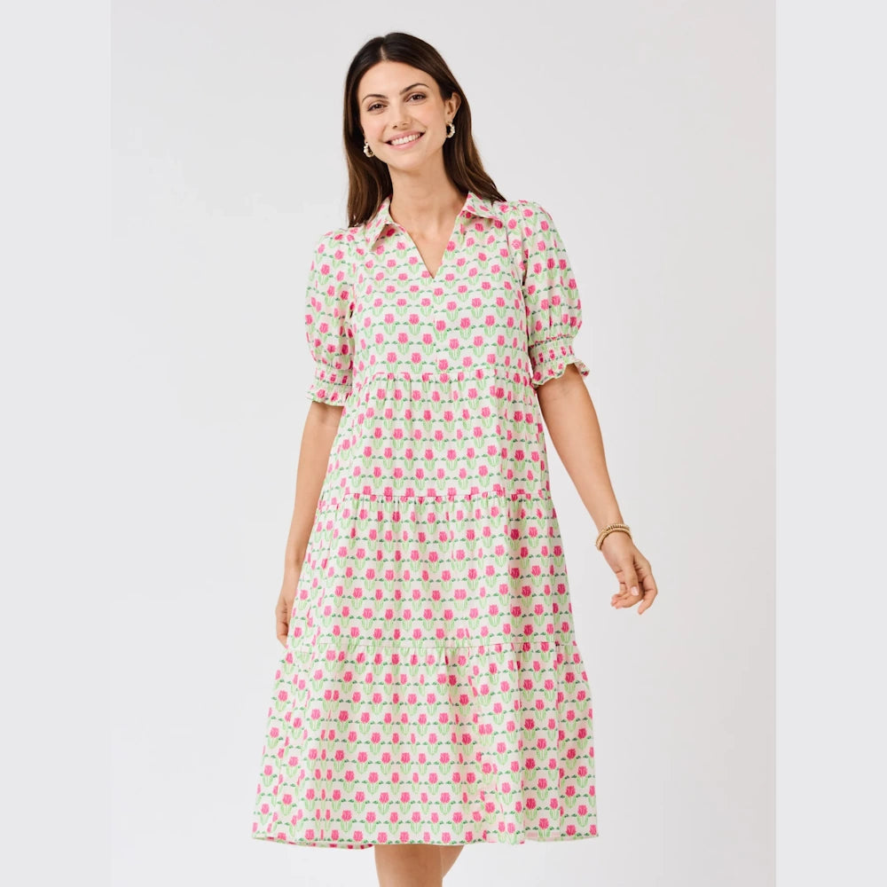 Woman wearing a white tiered midi dress with a pink and green floral tulip pattern, puff sleeves, and a collared neckline.