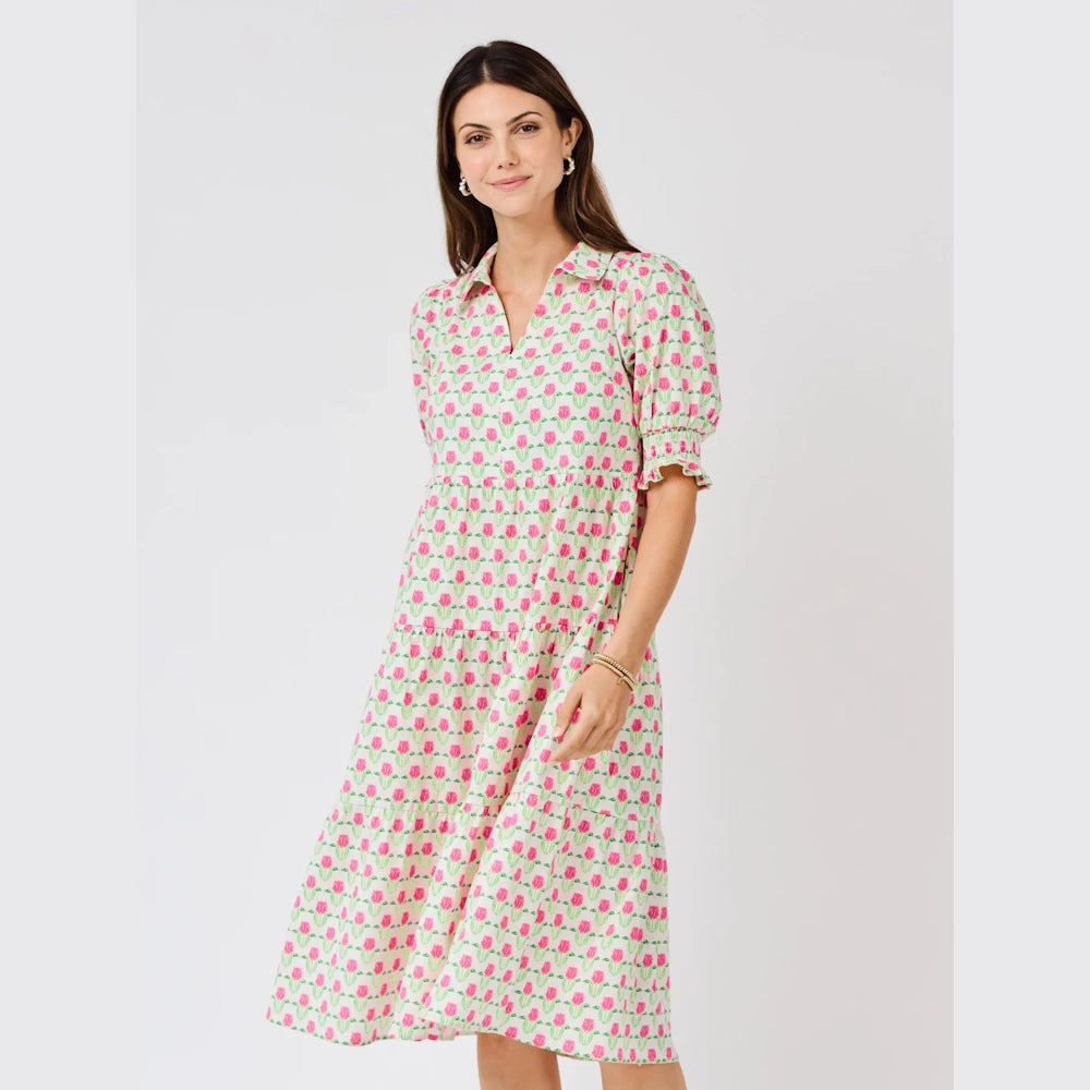 Woman wearing a tiered midi dress with a green and pink floral tulip pattern, collared neck, and puff sleeves.