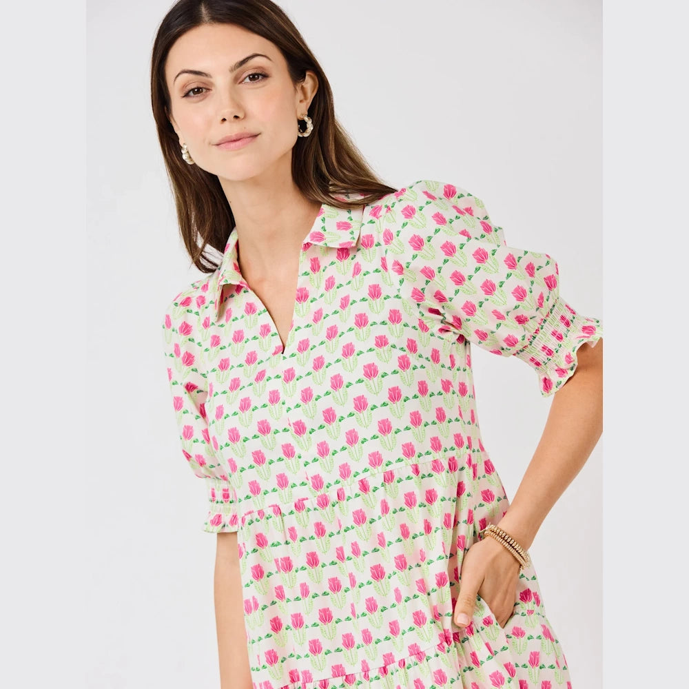 Woman in a white dress with a pink floral print, featuring puff sleeves and a collar.