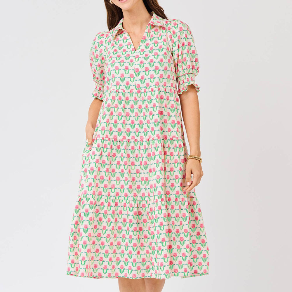 Woman wearing a tiered, knee-length dress with a pink and green floral tulip pattern and puffed sleeves.