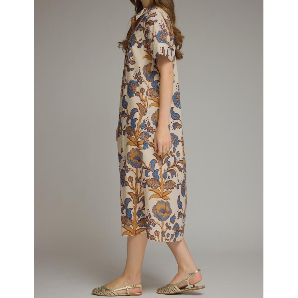 Side profile view of a woman wearing a beige floral midi shirt dress with blue and brown patterns and short sleeves.