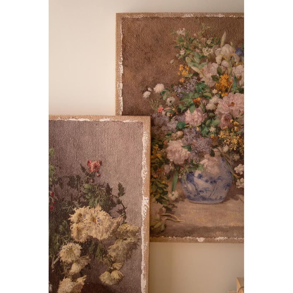 Angle shot of two vintage floral canvas prints on burlap with distressed white borders overlapping.