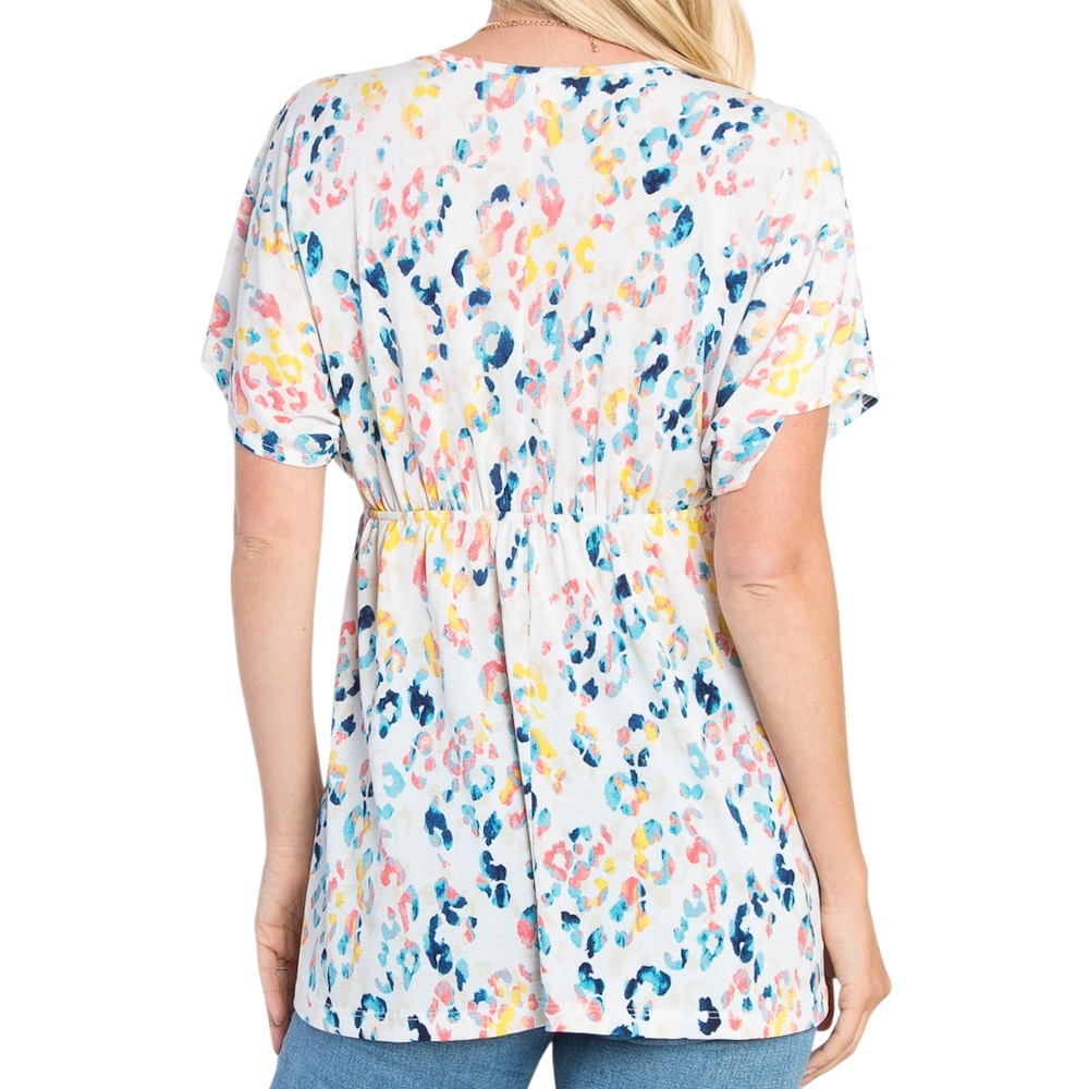 Back view of a person wearing a white, short-sleeved babydoll top with a colorful abstract print.