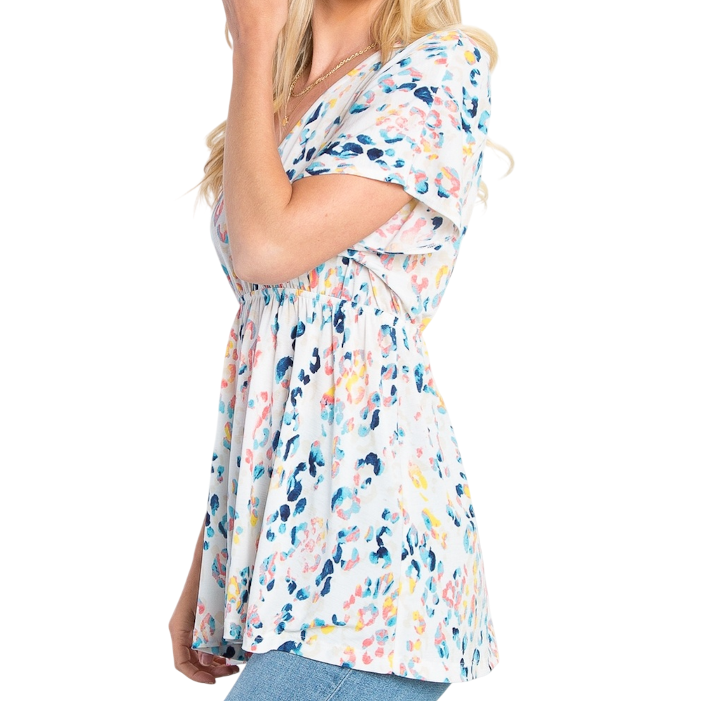 Woman in a floral print babydoll short sleeve top, shown from the side against a white background.