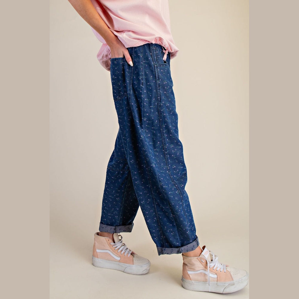 Floral printed washed barrel denim pants in dark blue with pink high-top sneakers and a pink shirt.