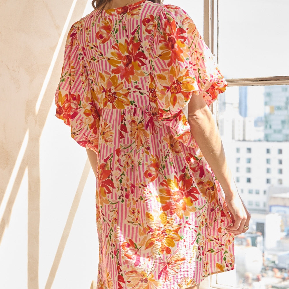 Back view of a pink striped babydoll dress with puff sleeves and vibrant orange and yellow floral pattern.