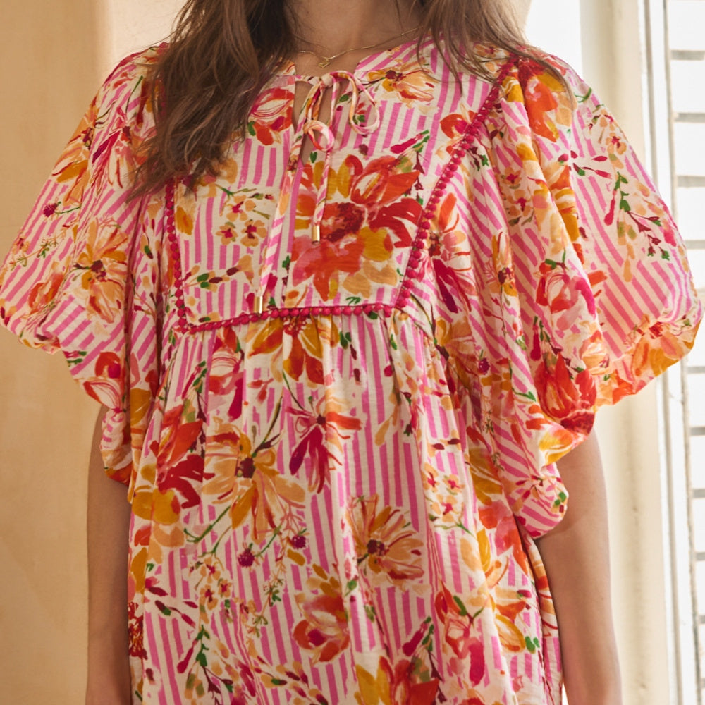 Pink striped babydoll dress featuring vibrant orange and red florals, puff sleeves, and a tied neckline.